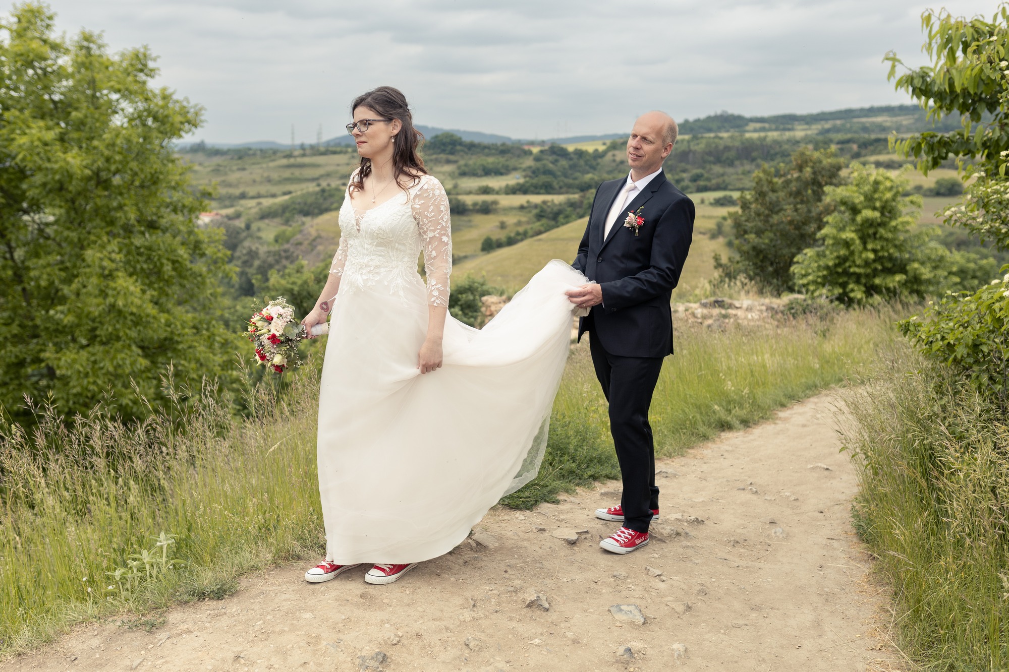 Svatba v Tetíně u Berouna - ženich pomáhá nevěstě s šaty